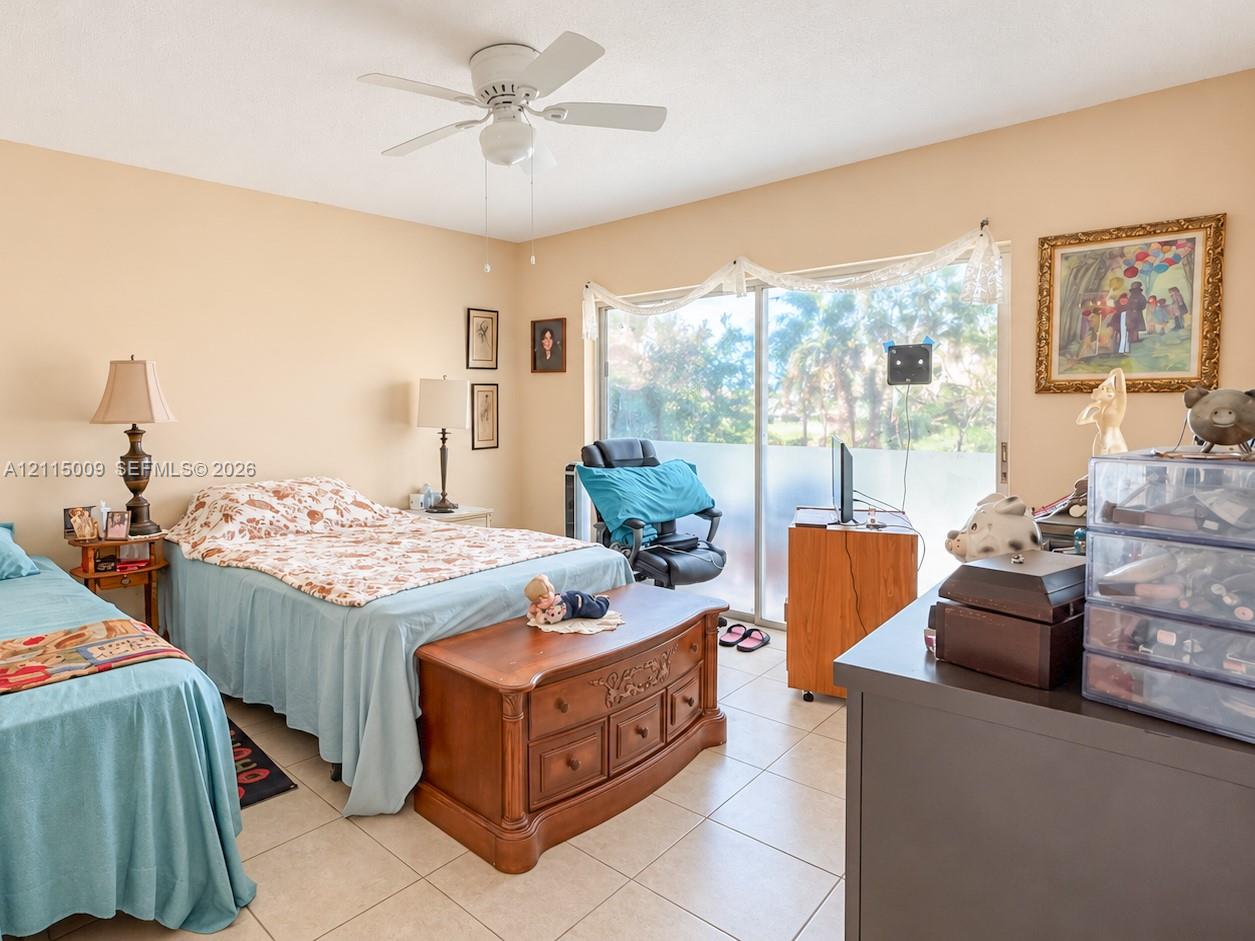 Neutral-toned interior featuring ceramic tile flooring, a white ceiling fan with integrated lighting, and sliding glass doors with privacy tint