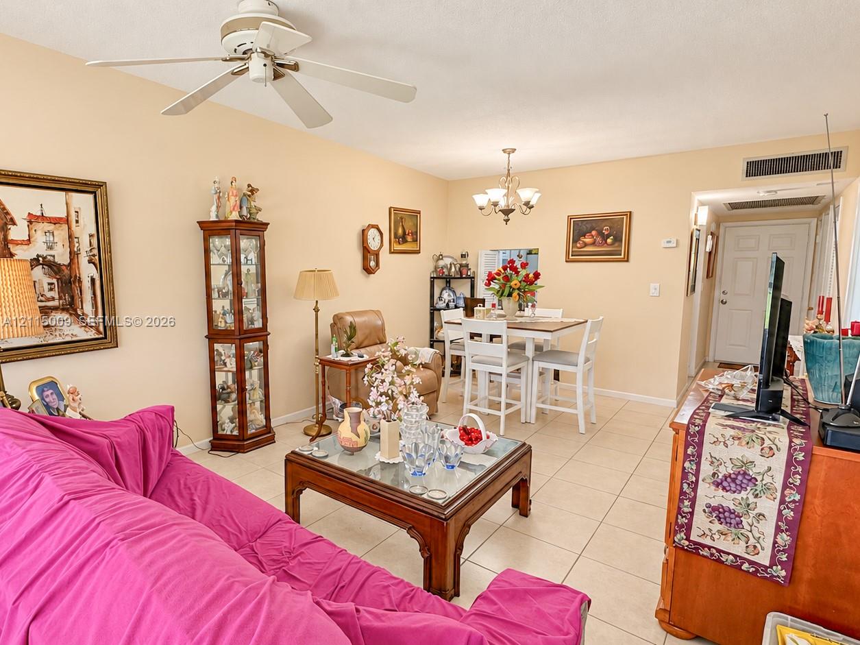 Living area featuring ceramic tile flooring, a multi-blade ceiling fan, and a multi-arm chandelier