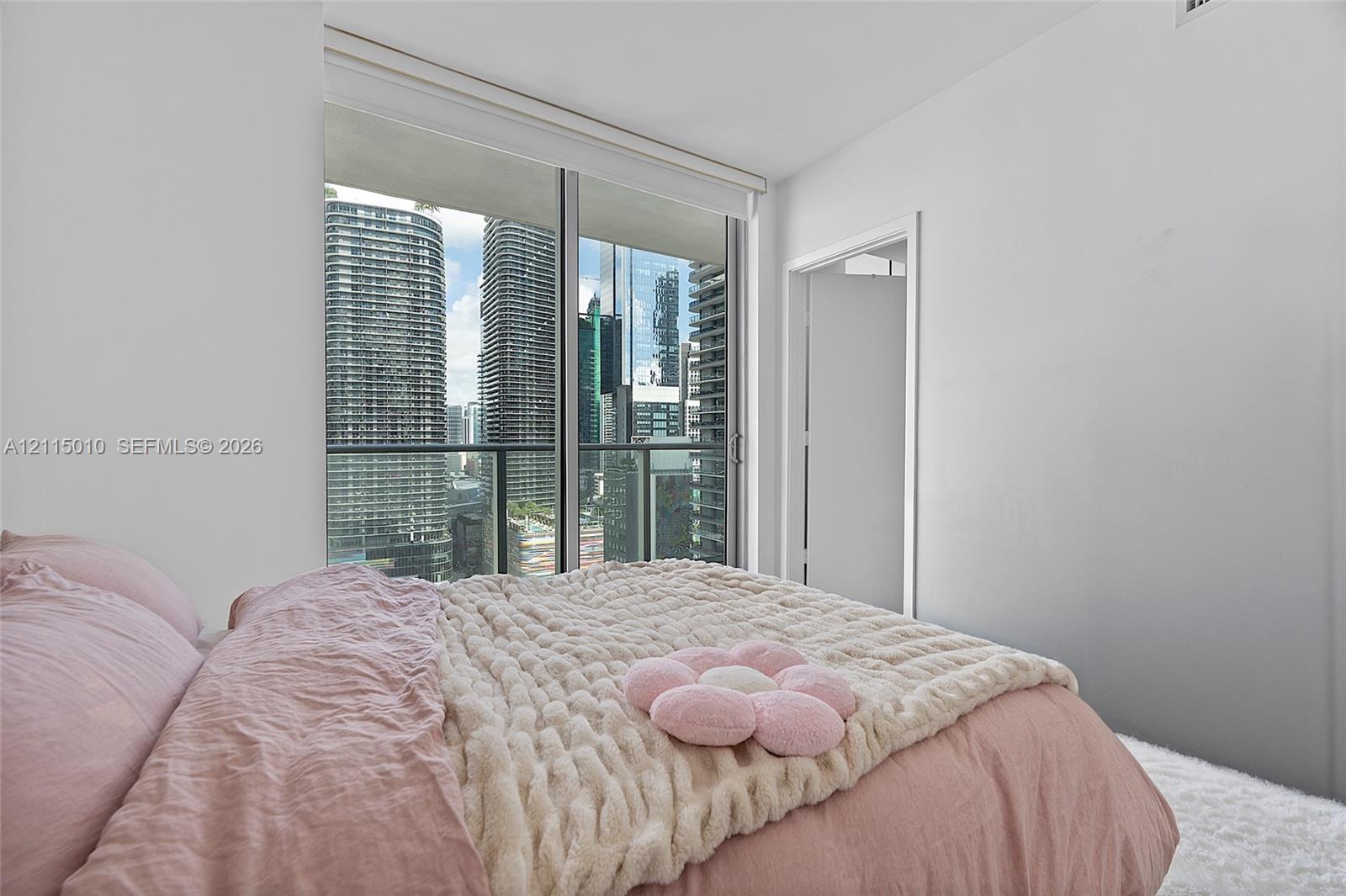 Floor-to-ceiling glass sliding doors, private balcony, and urban high-rise scenery