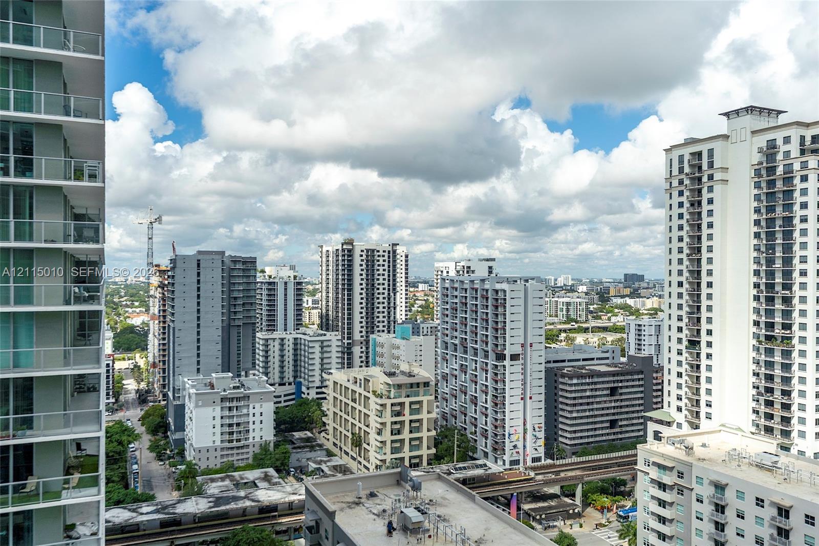 High-rise balcony featuring glass-panel railings and an expansive urban cityscape