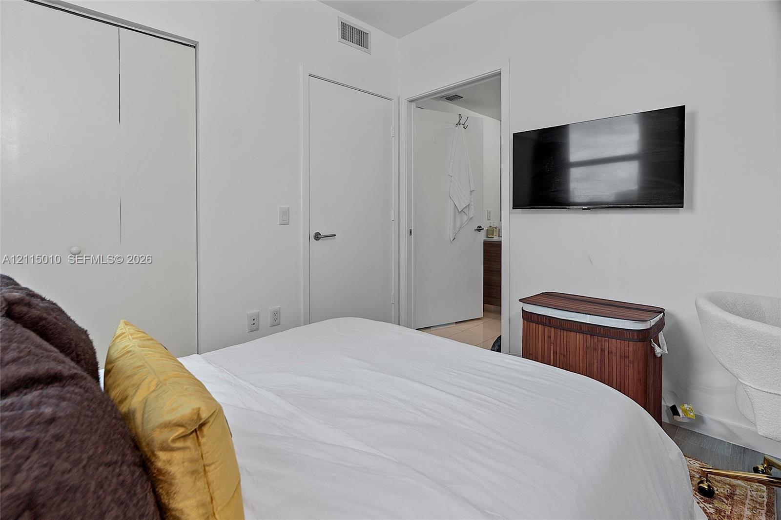 Neutral-toned room featuring a double-door reach-in closet and a wall-mounted flat-screen television