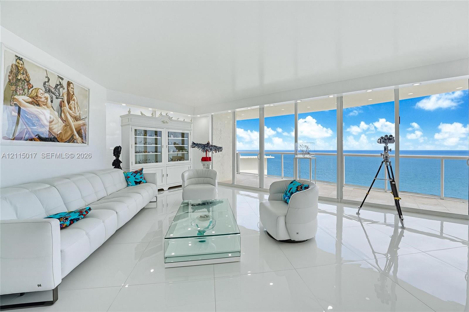 Spacious living area featuring polished tile flooring, floor-to-ceiling glass wall, built-in display cabinetry, and an expansive balcony with glass railings
