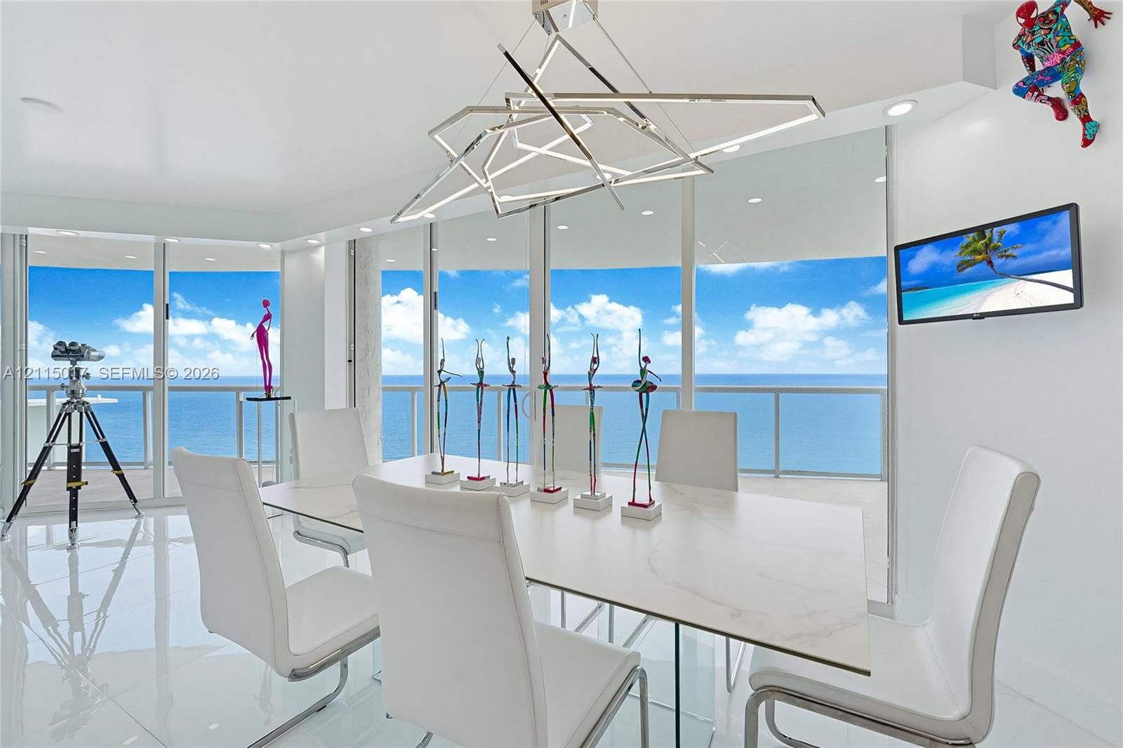 Floor-to-ceiling glass walls, geometric metal chandelier, polished tile flooring, recessed lighting, and glass-railed balcony