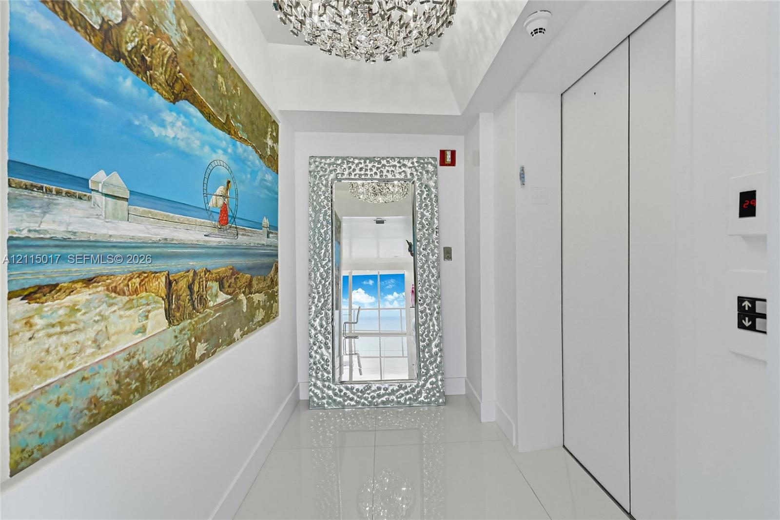 Private elevator entry featuring polished tile flooring, crisp white walls, and a recessed ceiling accented by a tiered crystal chandelier
