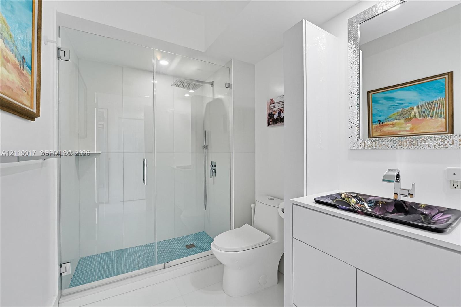 Glass-enclosed walk-in shower with rainfall showerhead and mosaic tile flooring, white vanity with vessel sink, and chrome fixtures