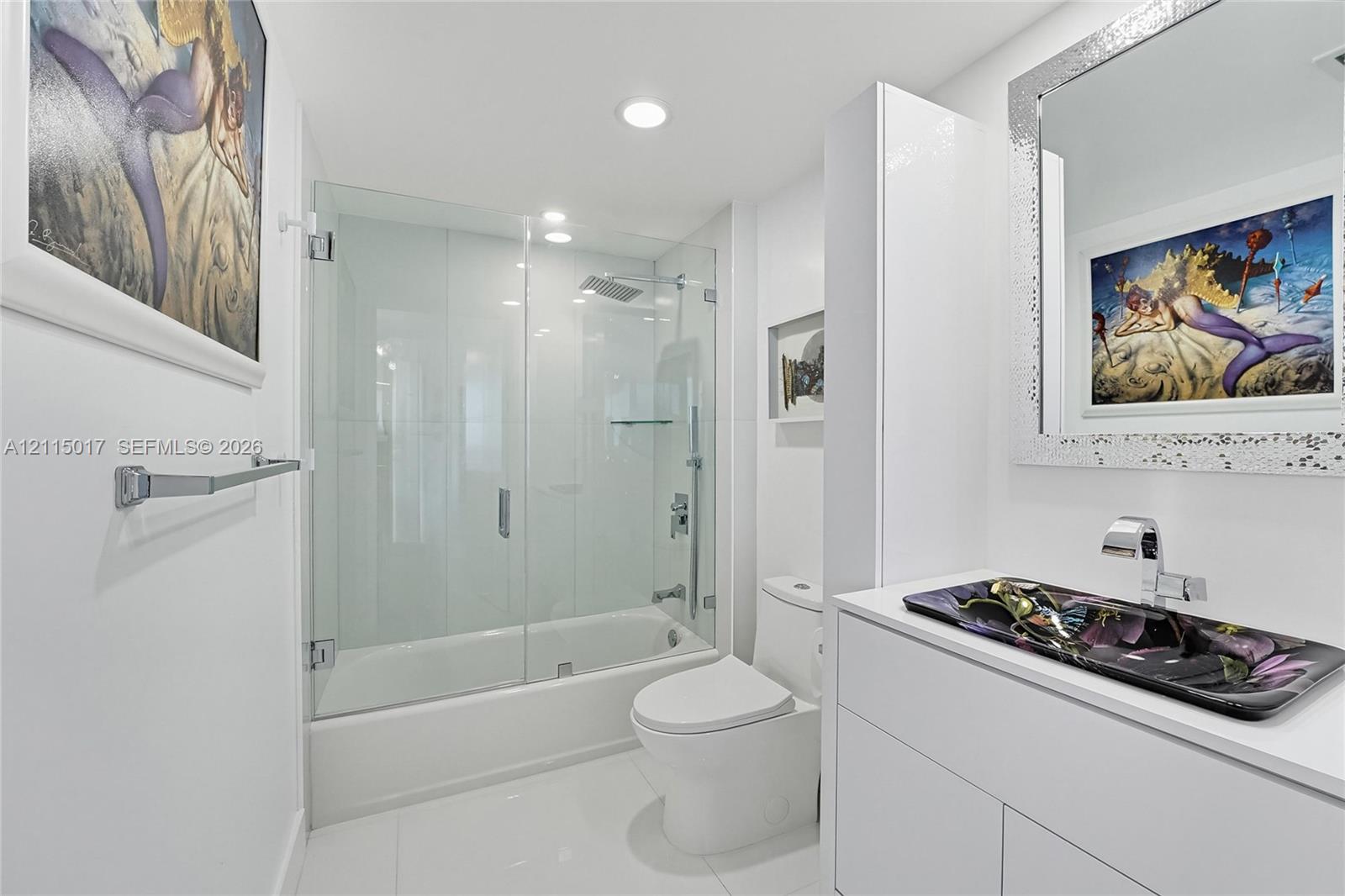 Bathroom featuring a white vanity cabinet, a glass vessel sink, chrome fixtures, and a glass-enclosed shower with a soaking tub