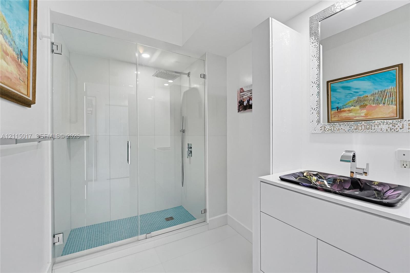 Walk-in shower featuring a glass enclosure, rainfall showerhead, and tile flooring, paired with a white vanity and rectangular vessel sink