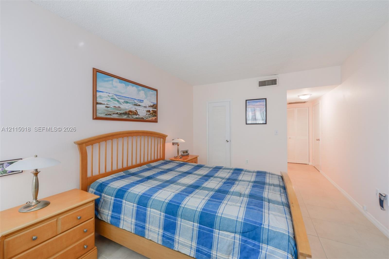Neutral-toned interior featuring smooth ceilings, ceramic tile flooring, and two white louvered closet doors