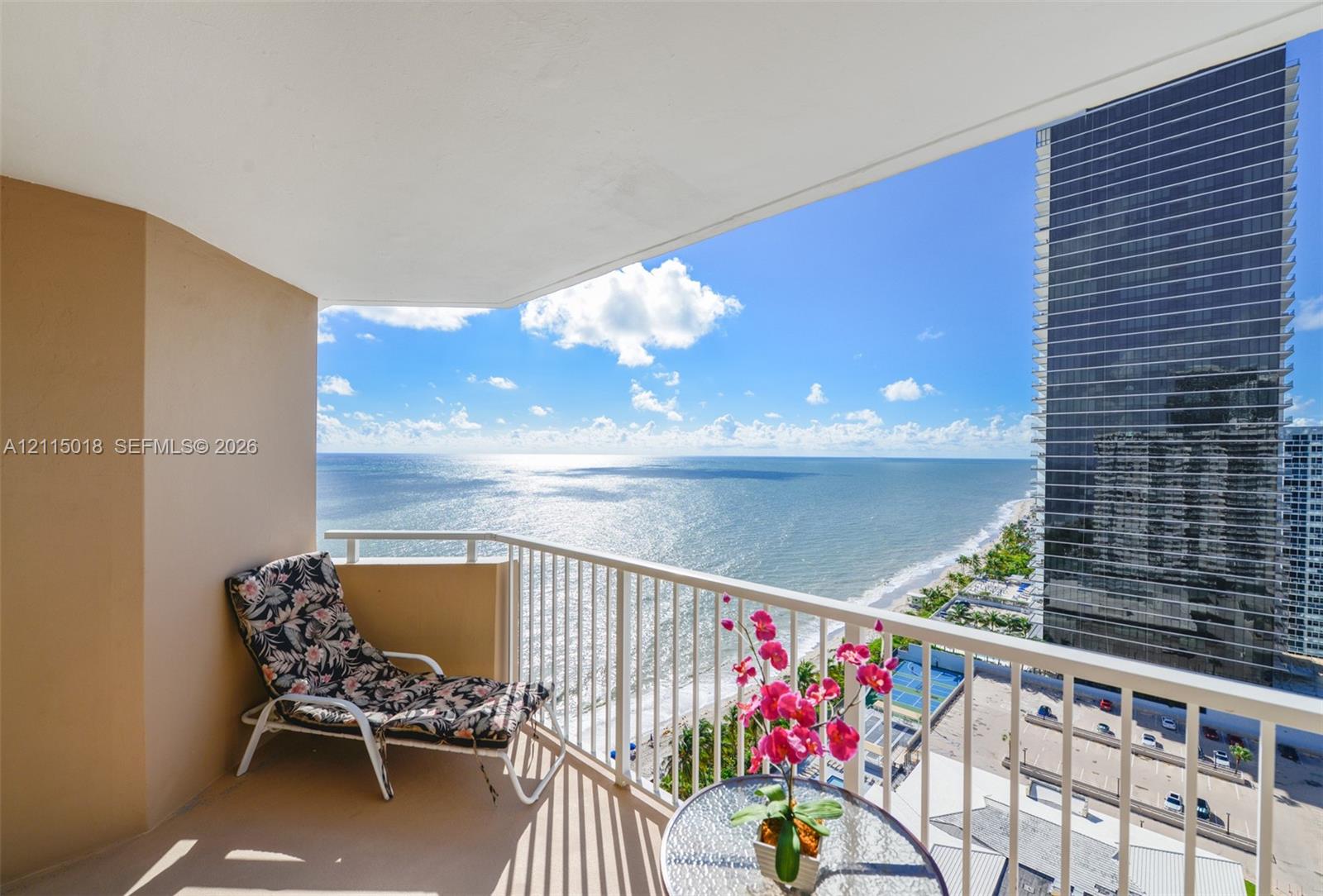 Covered private balcony featuring white metal railing and expansive ocean and coastal shoreline scenery
