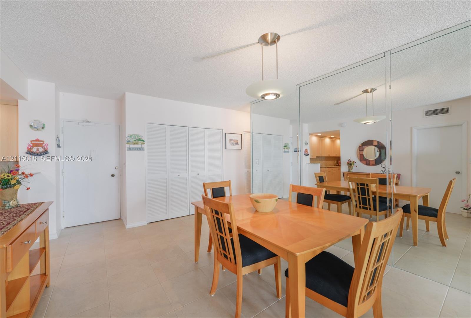 Tile flooring, floor-to-ceiling mirror paneling, and a modern pendant light fixture
