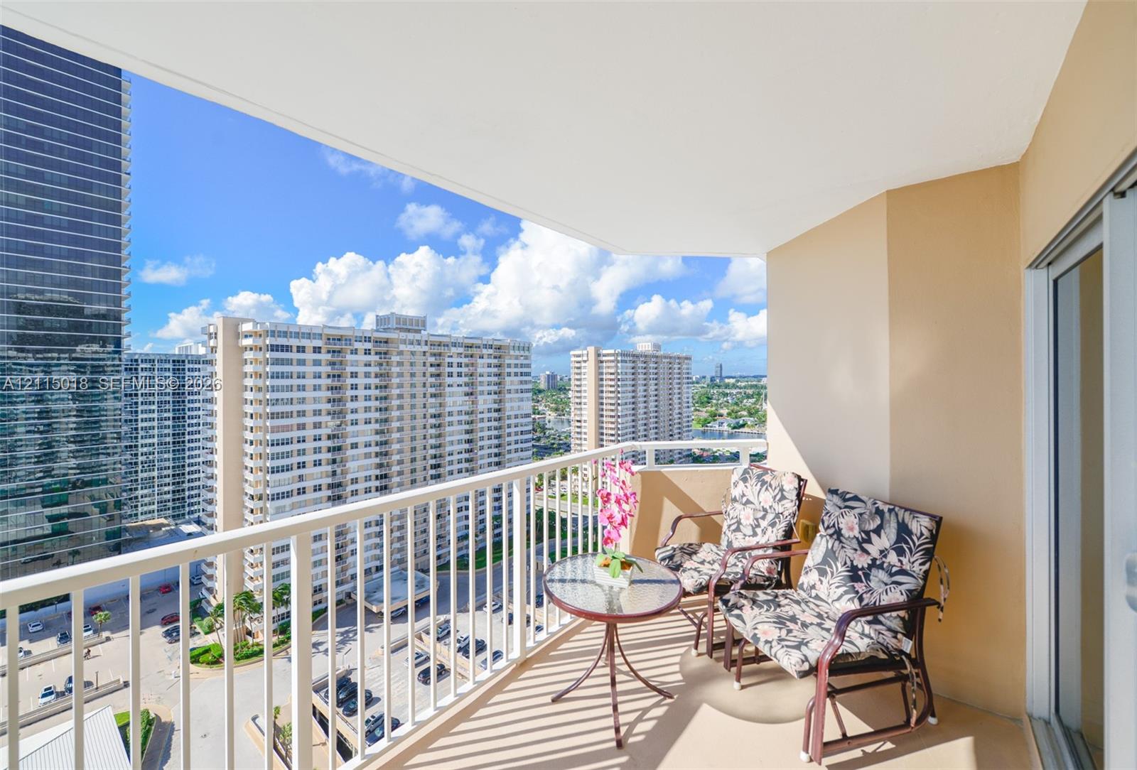 Private balcony featuring white metal railings and concrete flooring with urban scenery