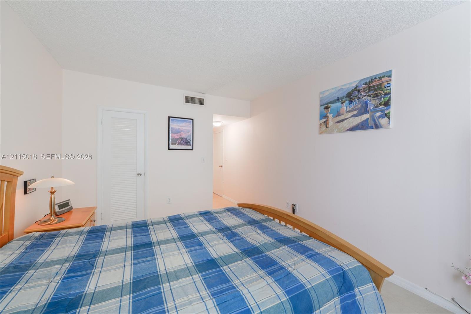 Interior room featuring neutral wall paint, a white louvered closet door, and a textured ceiling