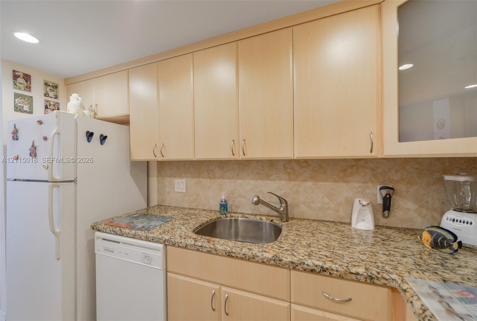 Flat-panel cabinetry, stone countertops, stainless steel undermount sink, recessed lighting, and tile backsplash