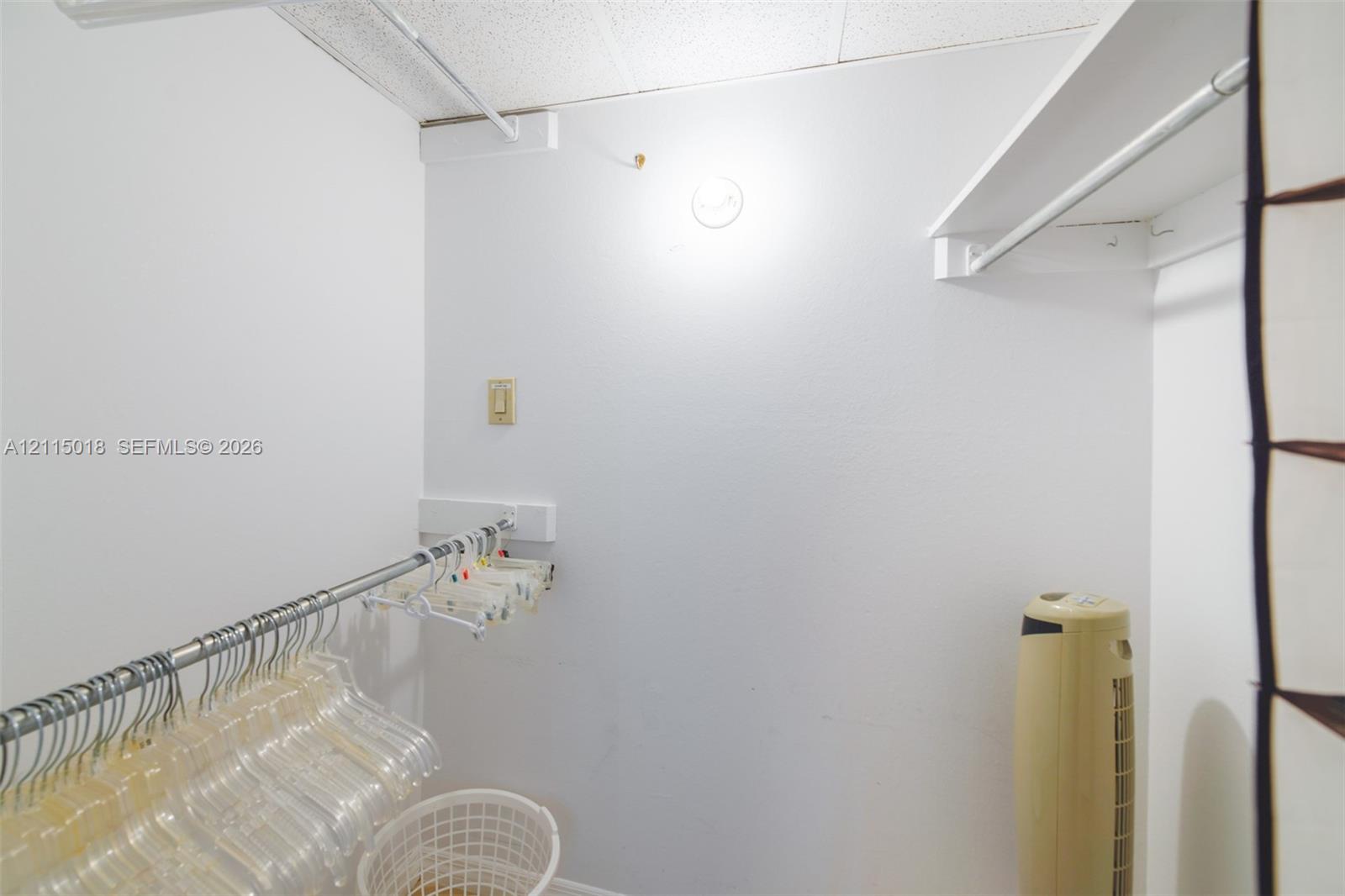 Walk-in closet featuring multi-level metal garment rods and built-in white shelving