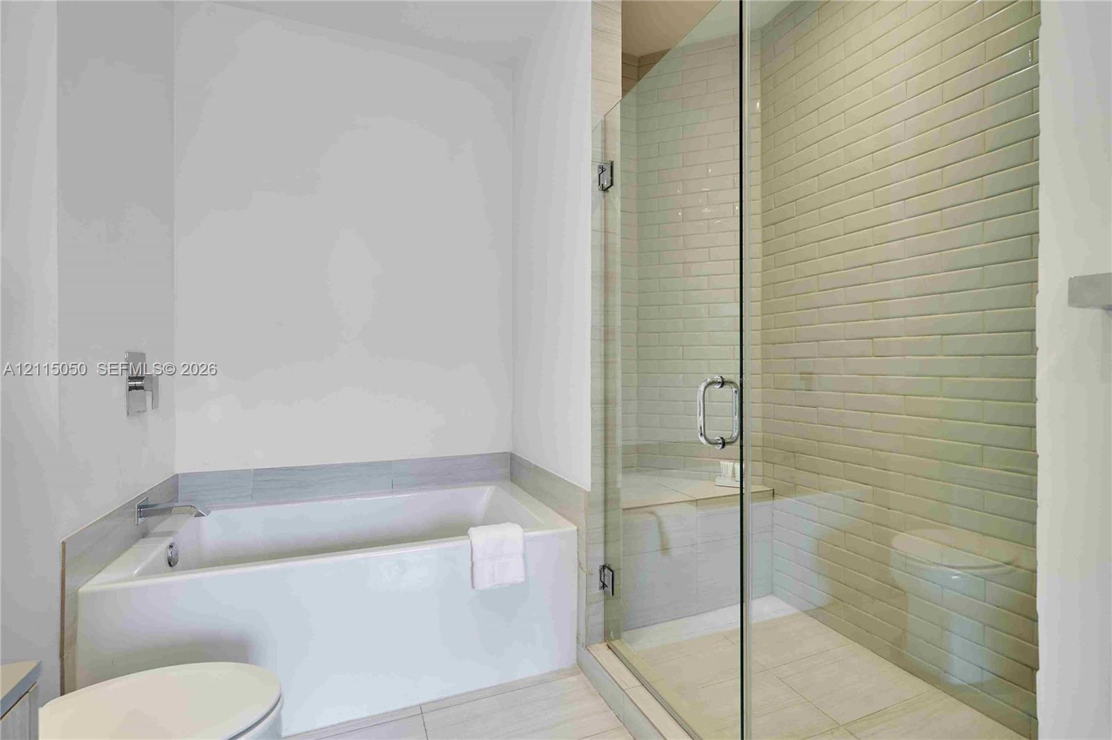 Built-in soaking tub with a tiled surround, walk-in shower enclosure with a glass door, and subway-style wall tiling