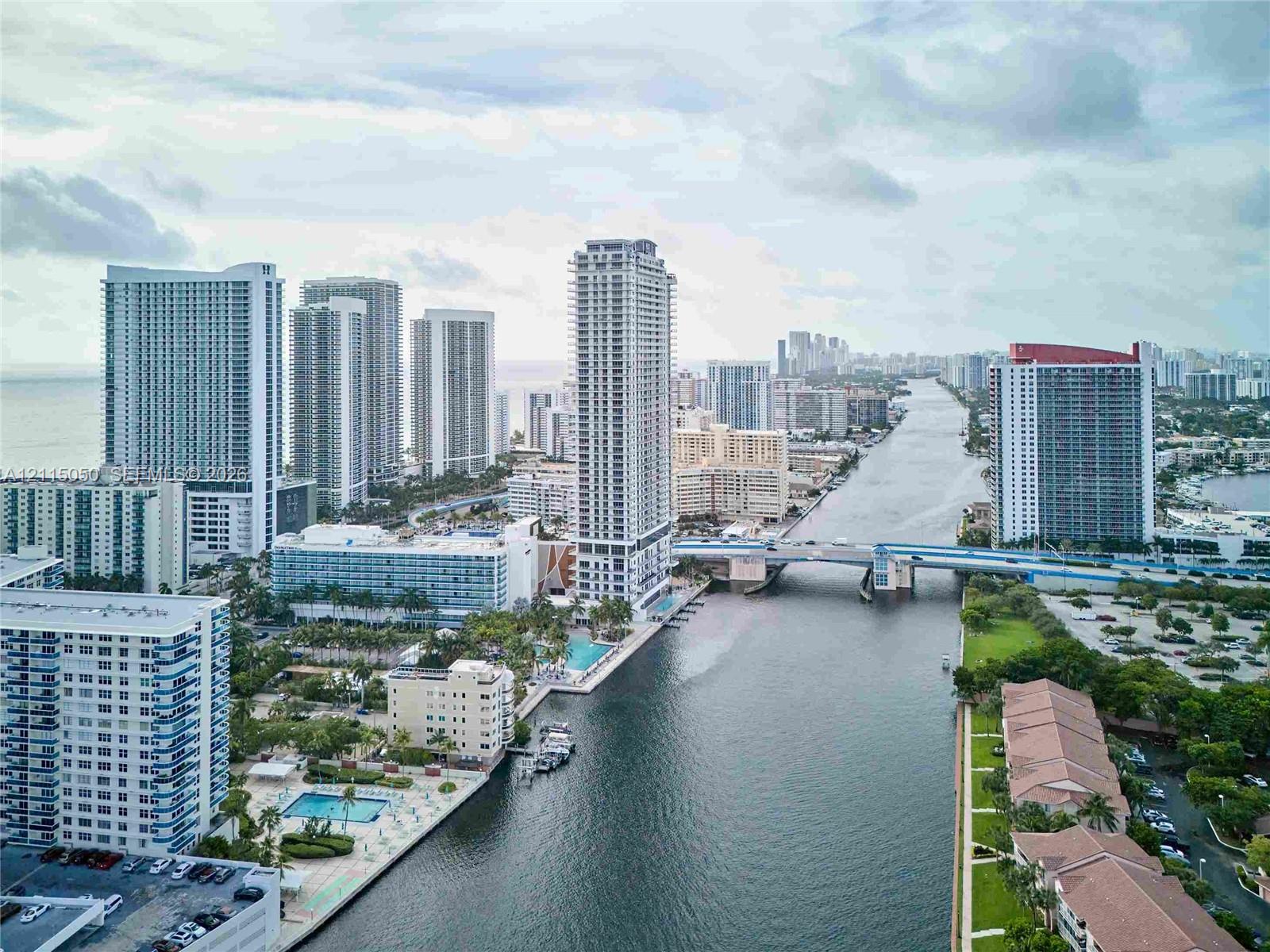 Aerial perspective featuring high-rise urban architecture, expansive waterway access, bridge infrastructure, and proximity to the coastline