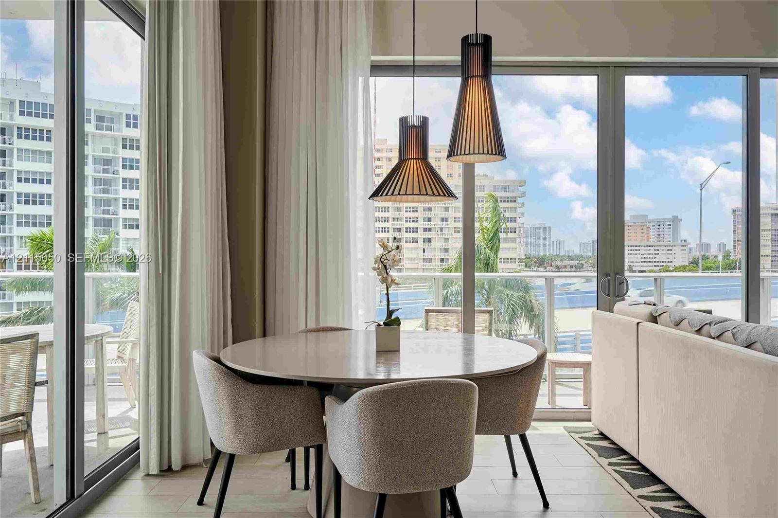 Floor-to-ceiling glass panel doors, dual tapered pendant lighting fixtures, and light-toned flooring Floor-to-ceiling glass panel doors, dual tapered pendant lighting fixtures, and light-toned flooring
