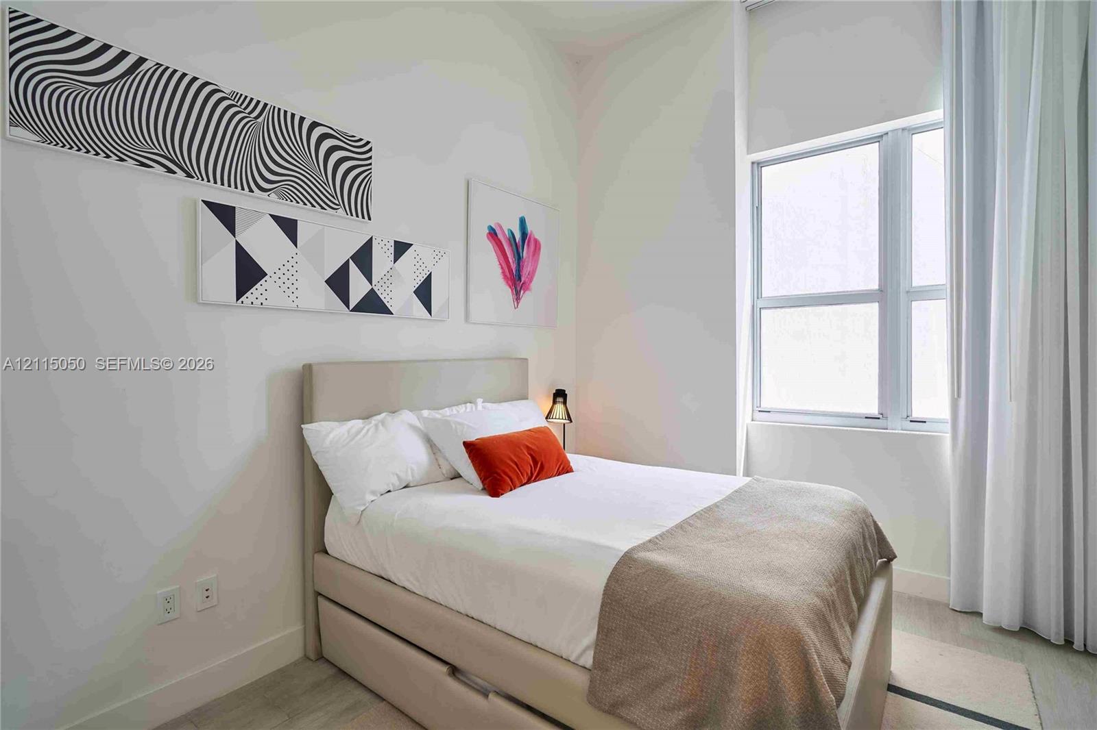 High ceilings, neutral wall finishes, and a large multi-pane window featuring floor-to-ceiling drapery