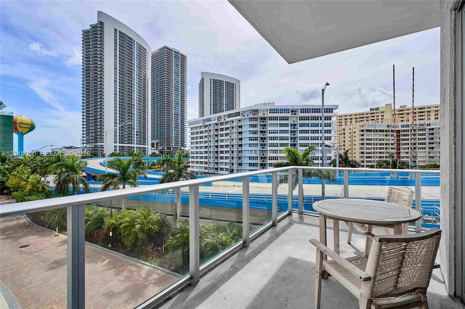 Private balcony featuring a concrete floor and a transparent glass railing with a metal frame