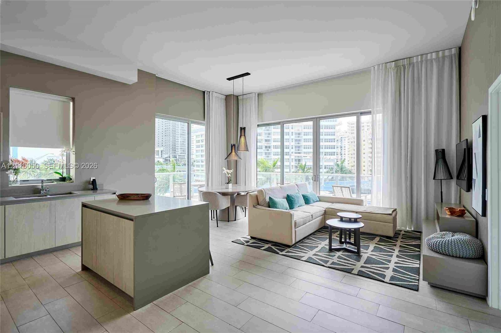 Open-concept interior featuring floor-to-ceiling glass panel doors, tile flooring, a central kitchen island with a neutral finish, and dual pendant light fixtures Open-concept interior featuring floor-to-ceiling glass panel doors, tile flooring, a central kitchen island with a neutral finish, and dual pendant light fixtures
