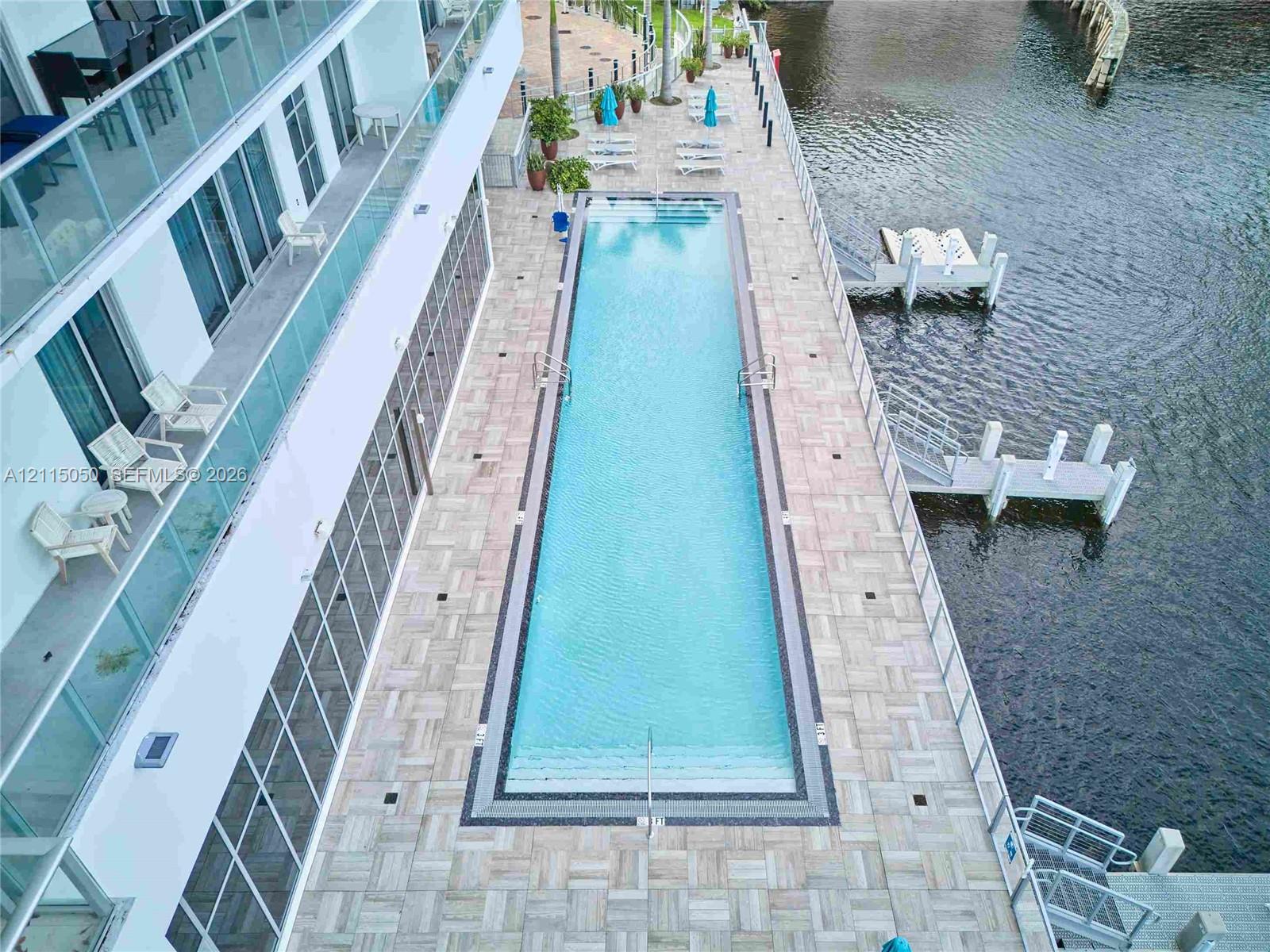 Linear swimming pool featuring tile decking, glass balcony railings, and dual private boat docks
