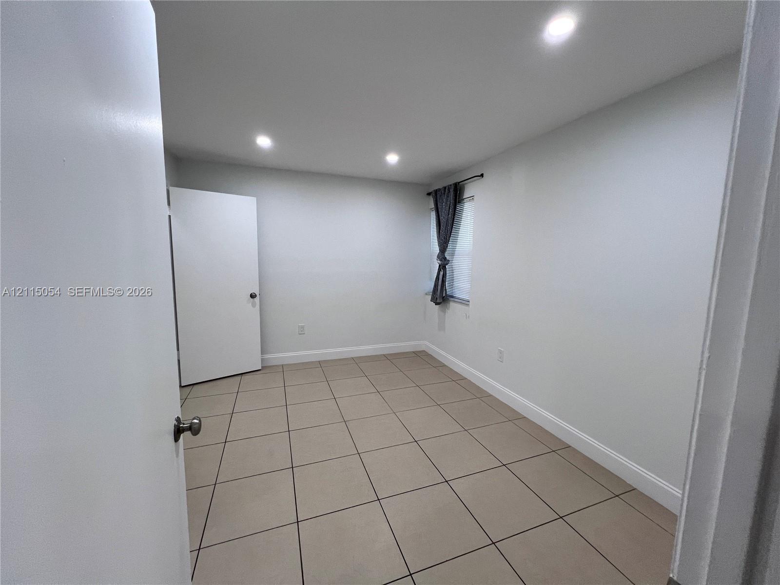 Interior room featuring large-format ceramic tile flooring, recessed ceiling lighting, and a single-panel interior door