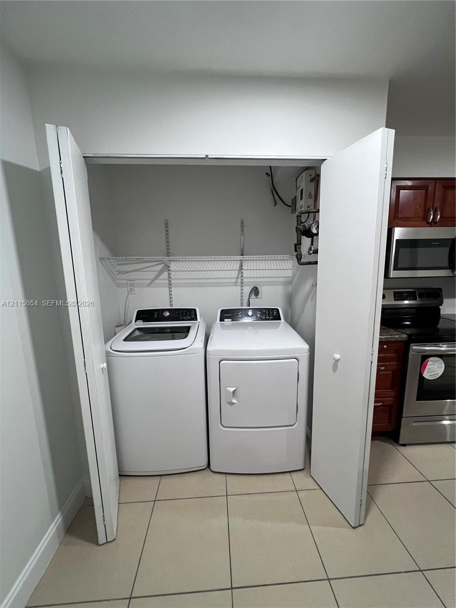 Laundry closet featuring bi-fold doors, white wire shelving, and tile flooring