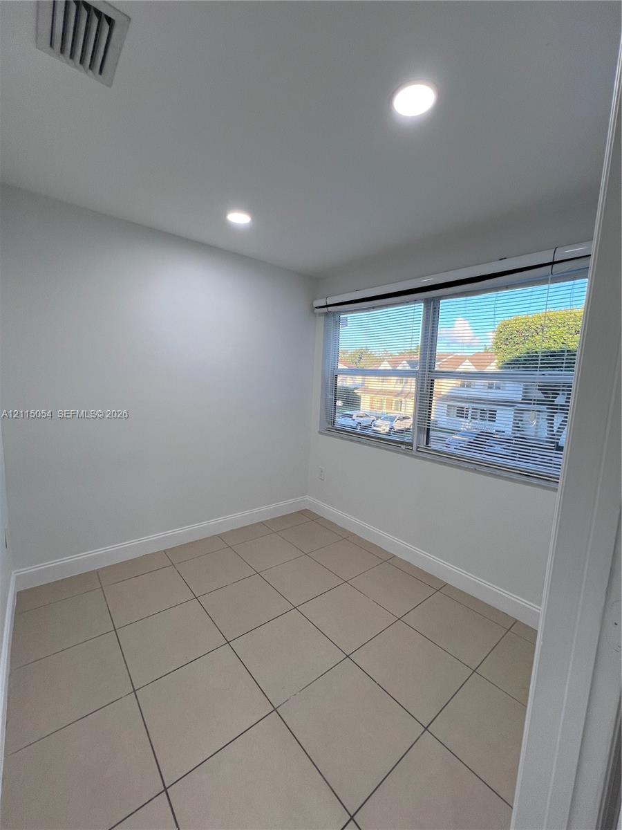 Interior room featuring large-format ceramic tile flooring, neutral wall tones, recessed lighting, and a double-pane horizontal sliding window