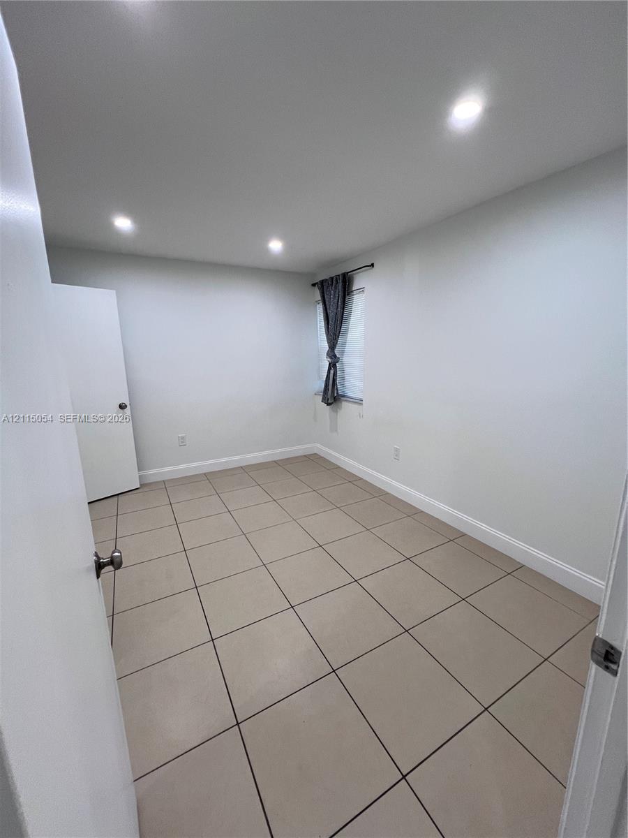 Interior space featuring ceramic tile flooring, recessed ceiling lighting, and a single window