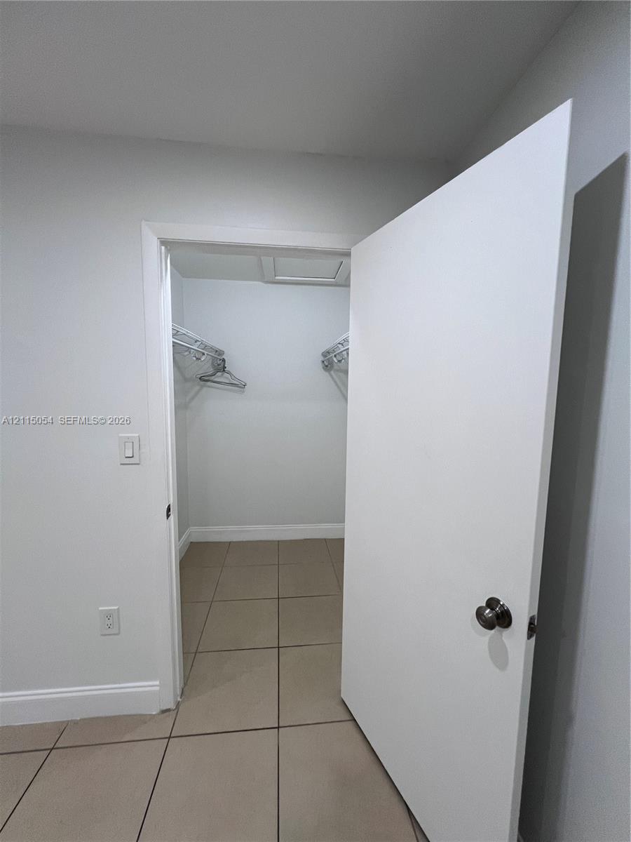 Walk-in closet featuring large-format neutral tile flooring and built-in wire shelving