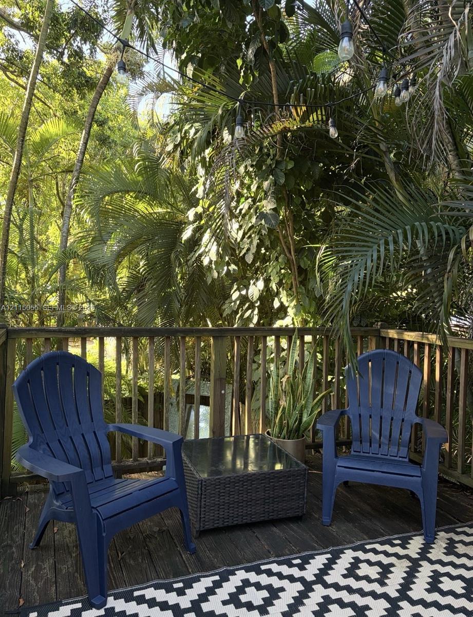 Outdoor wood deck featuring vertical wood railing, overhead string lighting, and mature perimeter trees