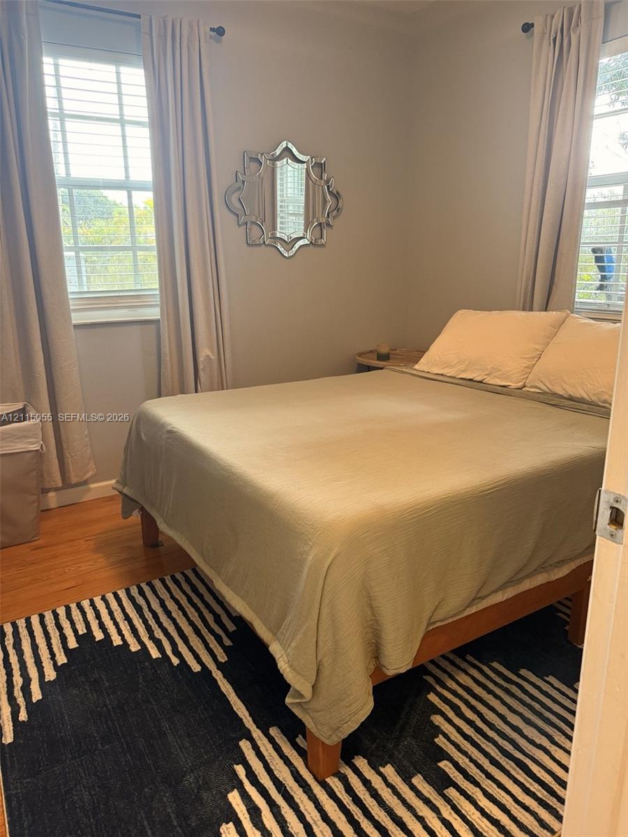 Wood-finish flooring, multiple windows with grid detailing, and neutral wall color