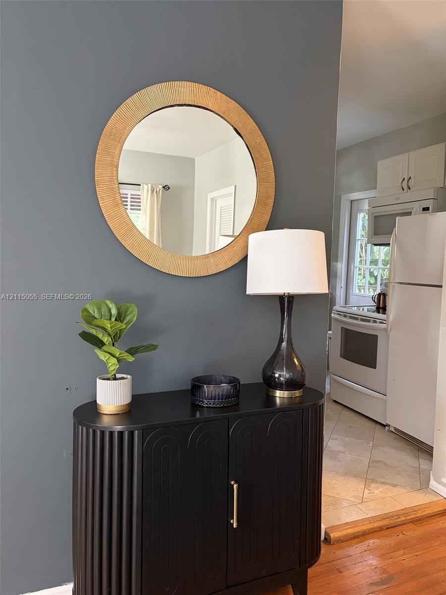 Charcoal-toned accent wall featuring a circular textured mirror and hardwood flooring