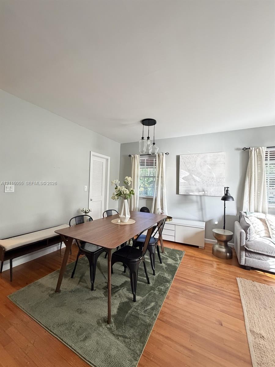 Wood-finish flooring, multi-pendant light fixture, and windows with horizontal blinds