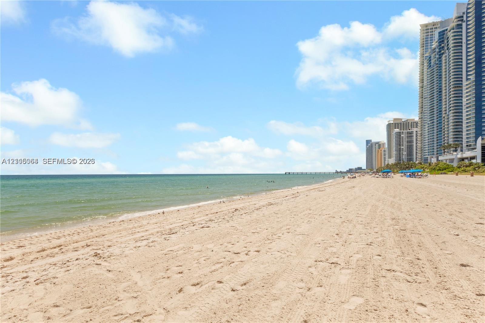 Sandy beachfront shoreline featuring direct ocean access and coastal proximity to high-rise structures