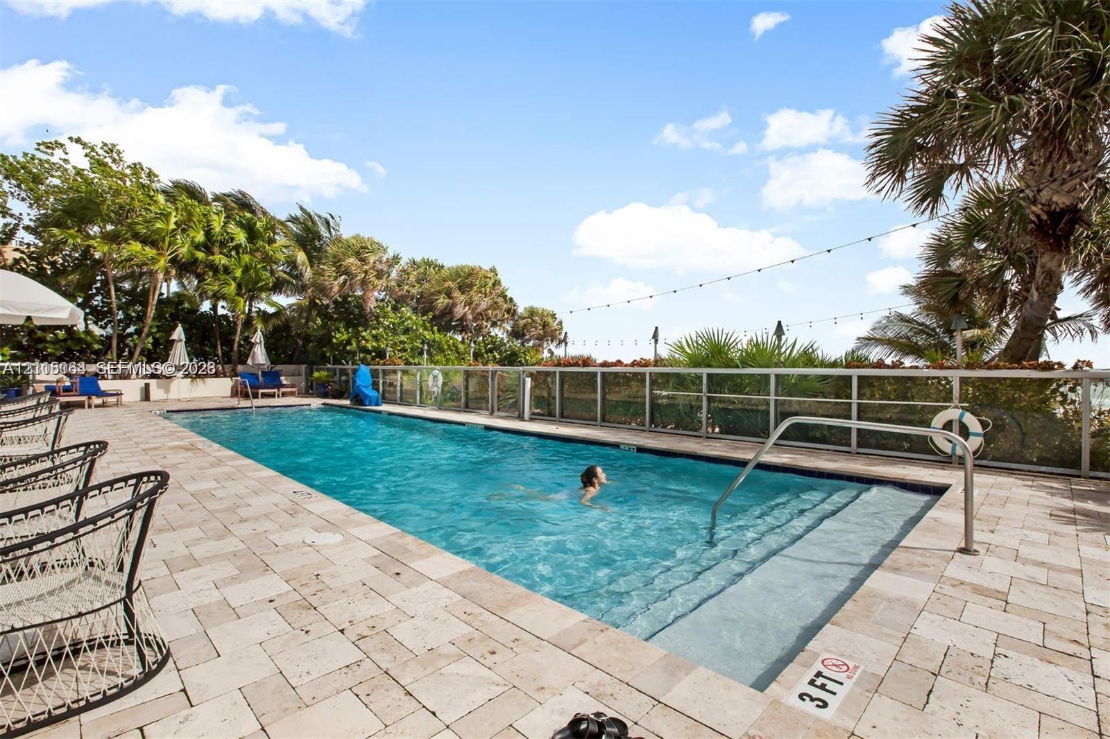 Rectangular in-ground swimming pool featuring stone-paver decking, perimeter metal fencing, and built-in entry steps