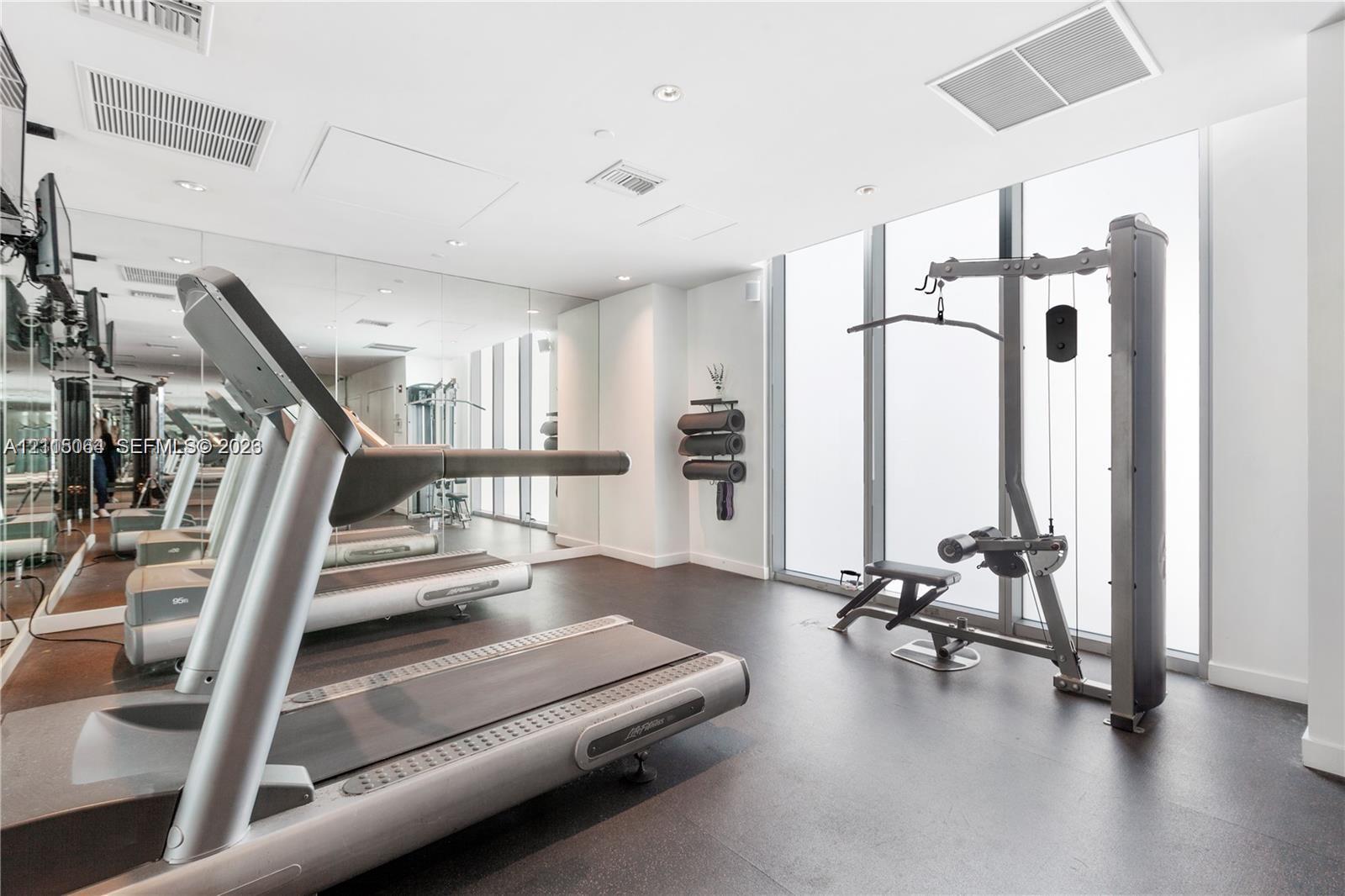 Fitness center featuring floor-to-ceiling windows, full-wall mirrors, recessed lighting, and resilient flooring