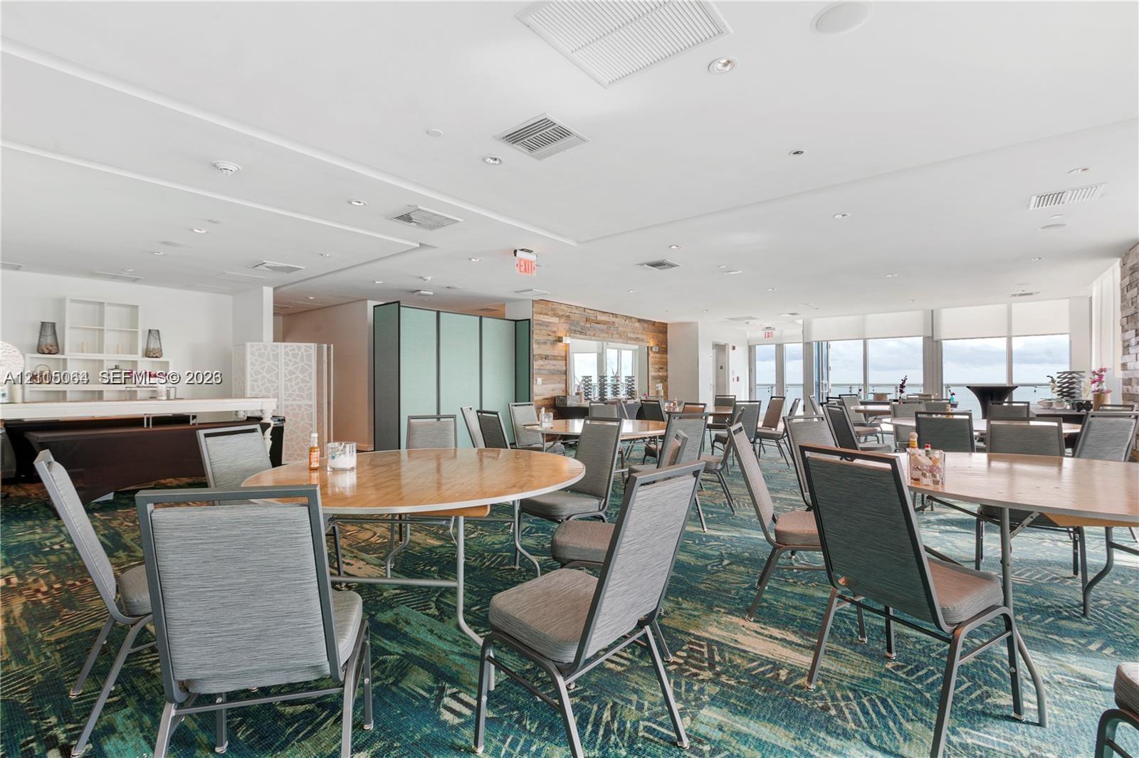 Open-concept room featuring a textured wood-plank accent wall, recessed lighting, and expansive floor-to-ceiling windows