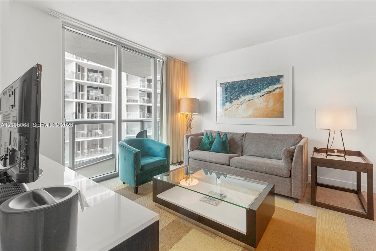 Floor-to-ceiling windows providing extensive natural light, private balcony access, and neutral wall finishes