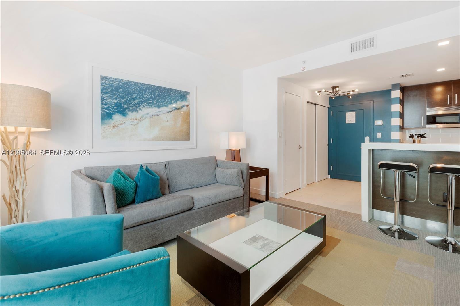 Open-concept space featuring dark wood-finish cabinetry, a white countertop breakfast bar, recessed lighting, and wall-to-wall carpeting