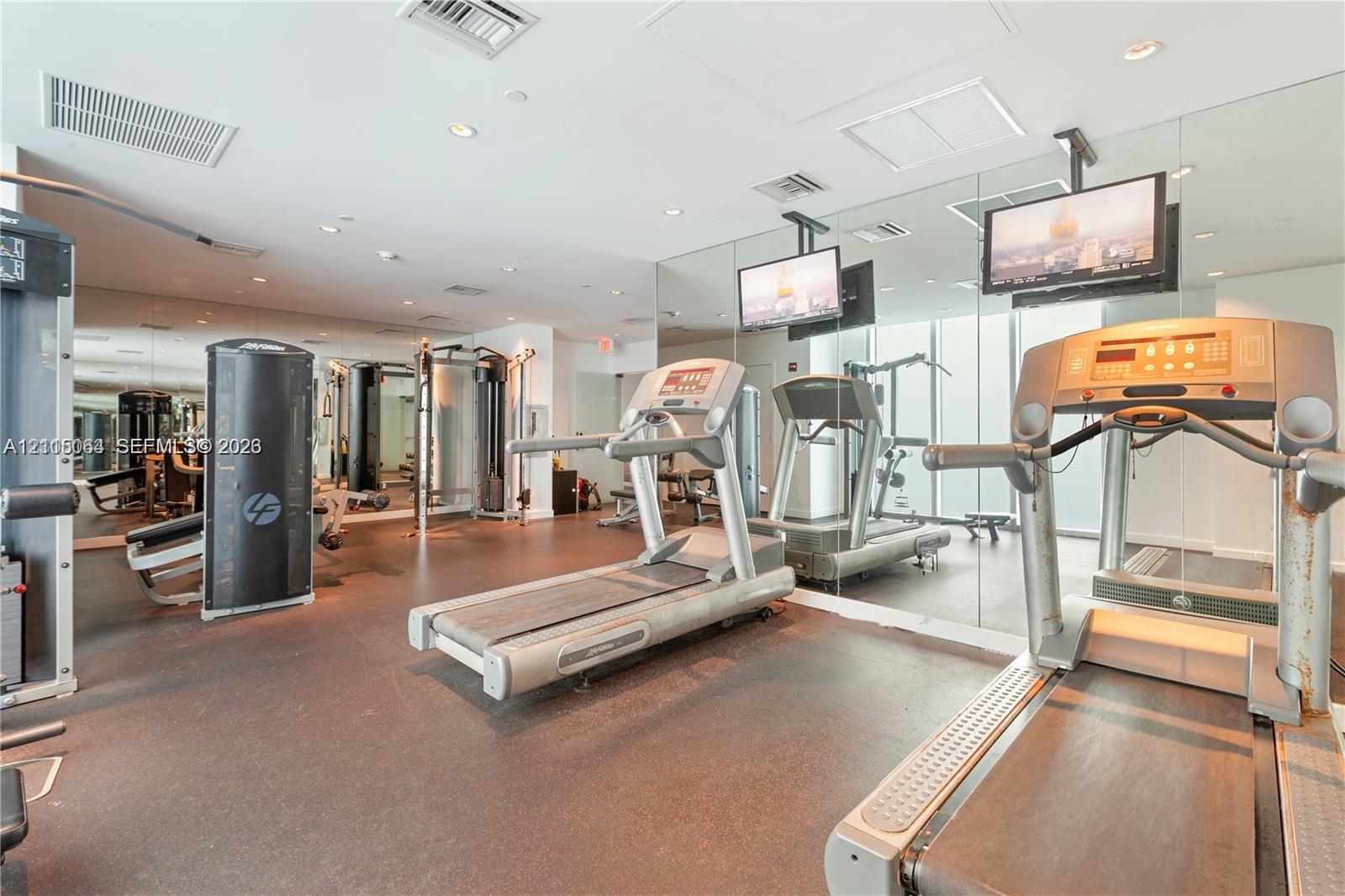 Fitness center featuring mirrored walls, recessed lighting, and rubberized flooring