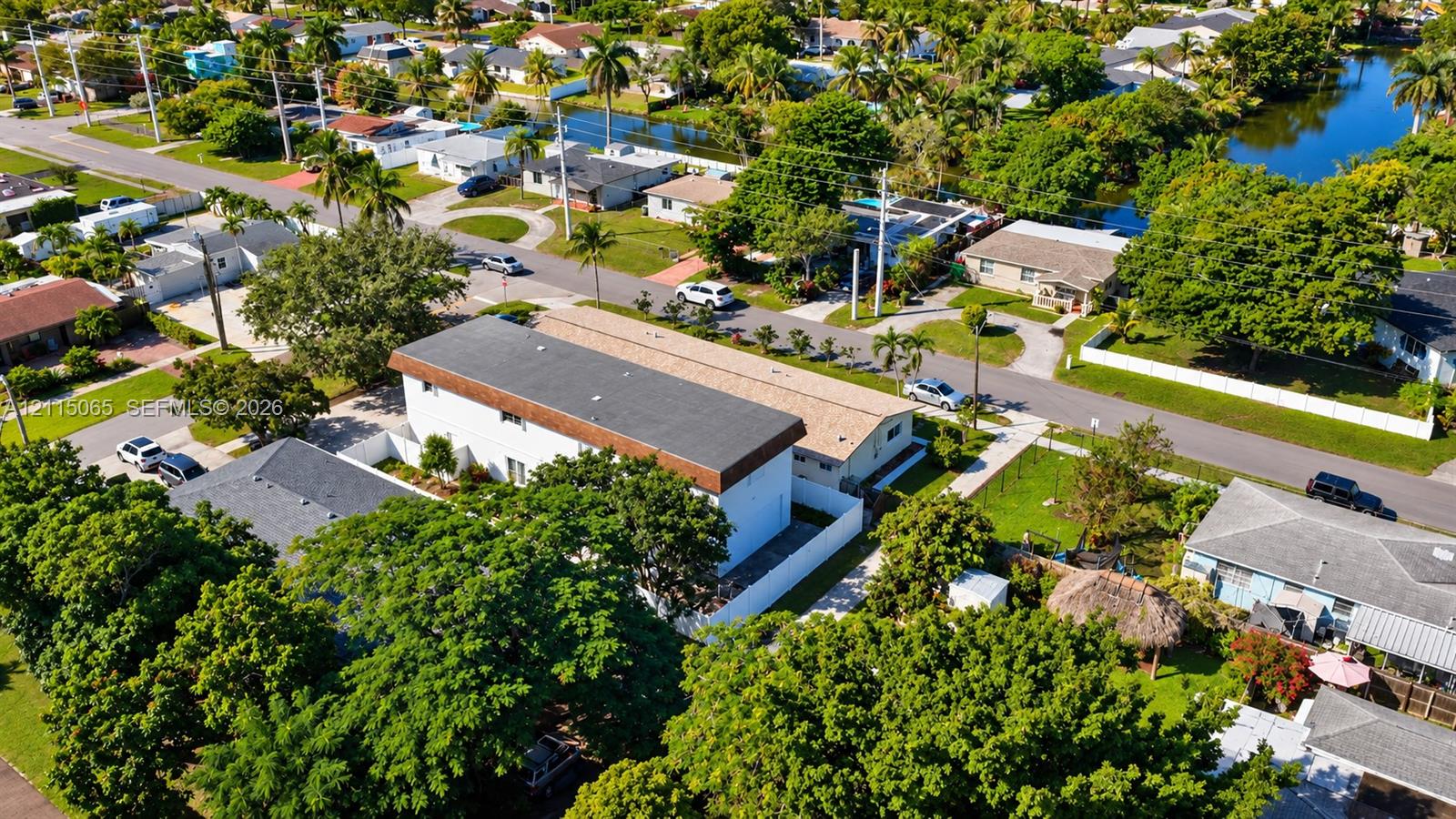 Aerial perspective of a multi-level structure featuring a flat roofline, white exterior siding, and a fenced perimeter