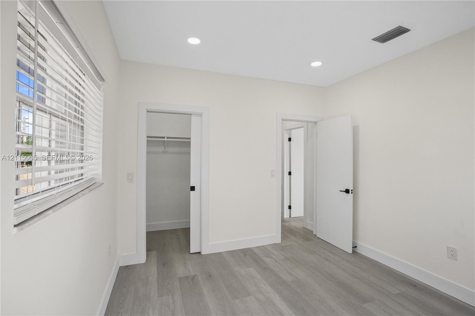 Interior room featuring wood-finish flooring, recessed lighting, a sliding closet door, and window blinds