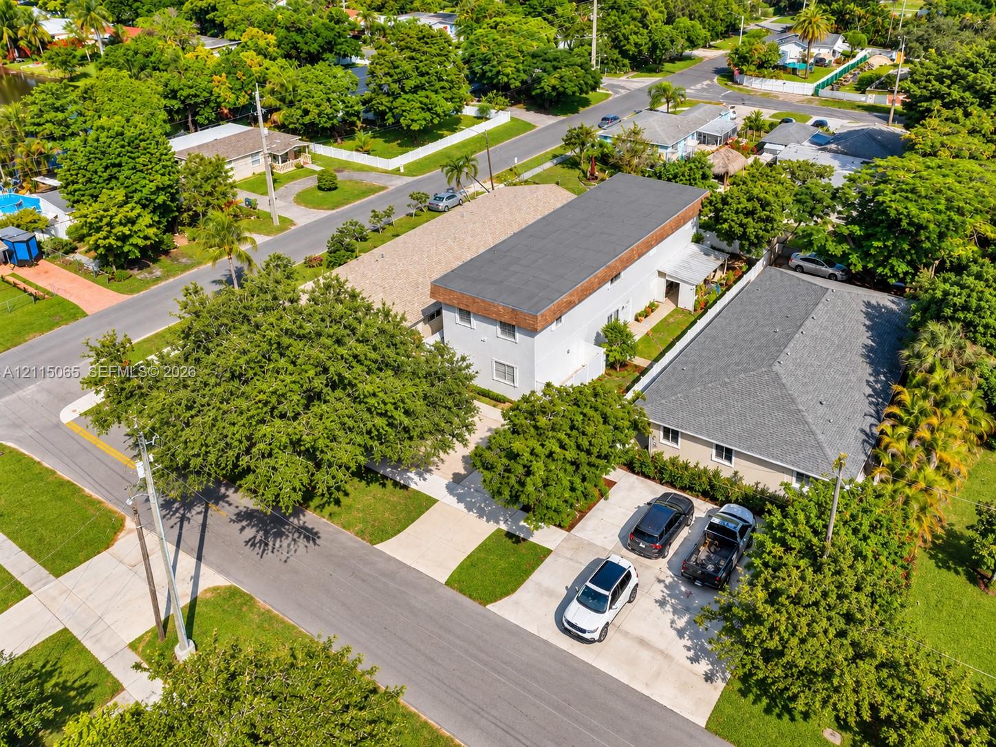 Multi-structure property featuring concrete driveways, mature canopy trees, low-slope roofing, and exterior masonry walls