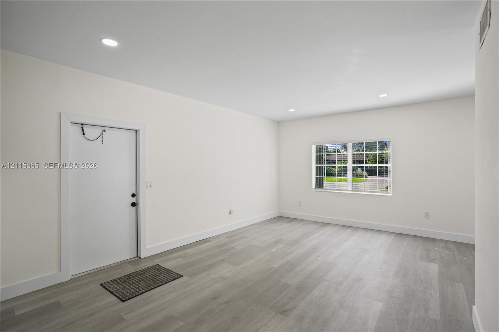 Neutral-toned wood-finish flooring, recessed lighting, and a multi-pane window