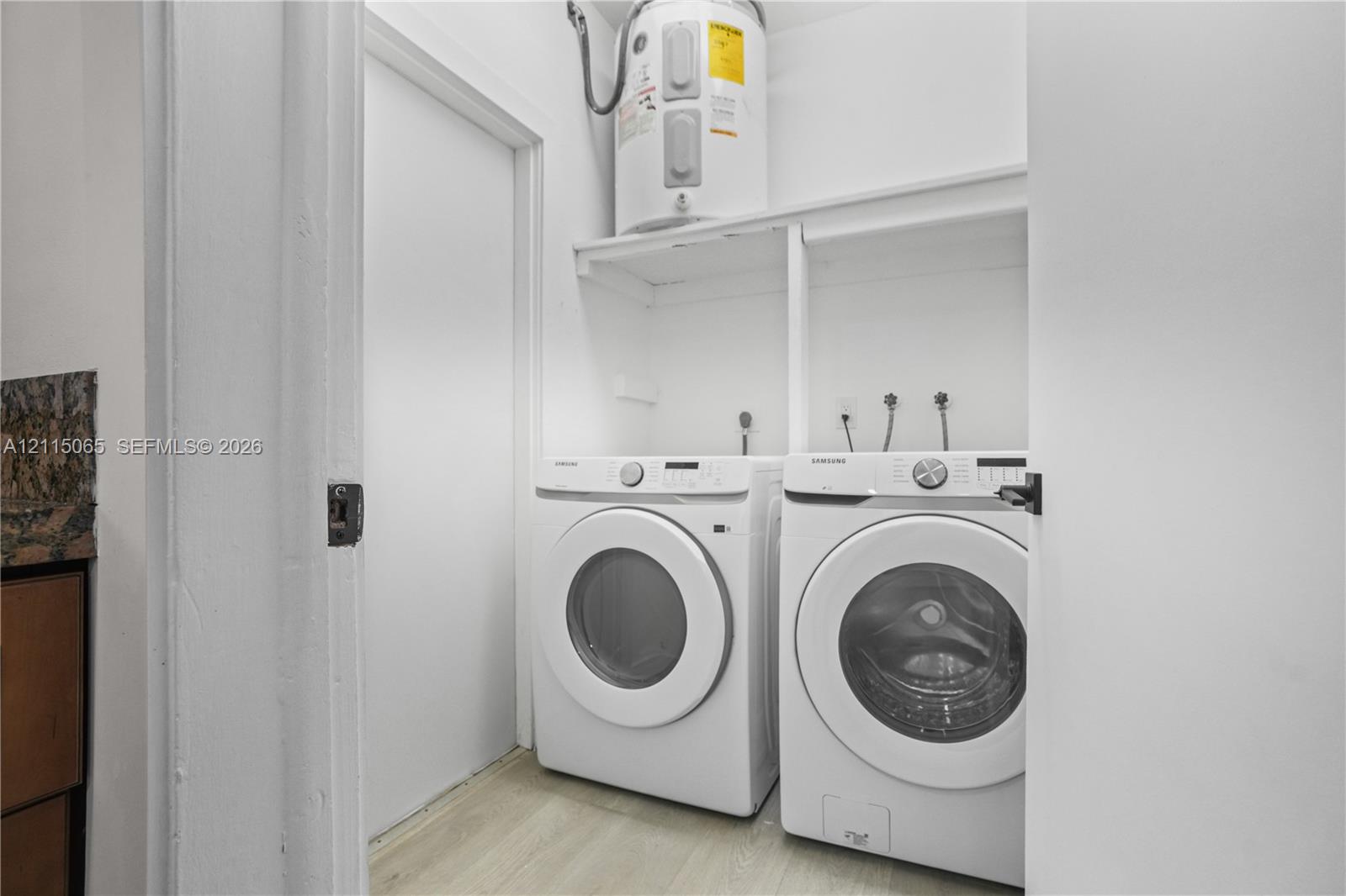 Utility area featuring wood-finish flooring, white shelving, and an integrated water heater