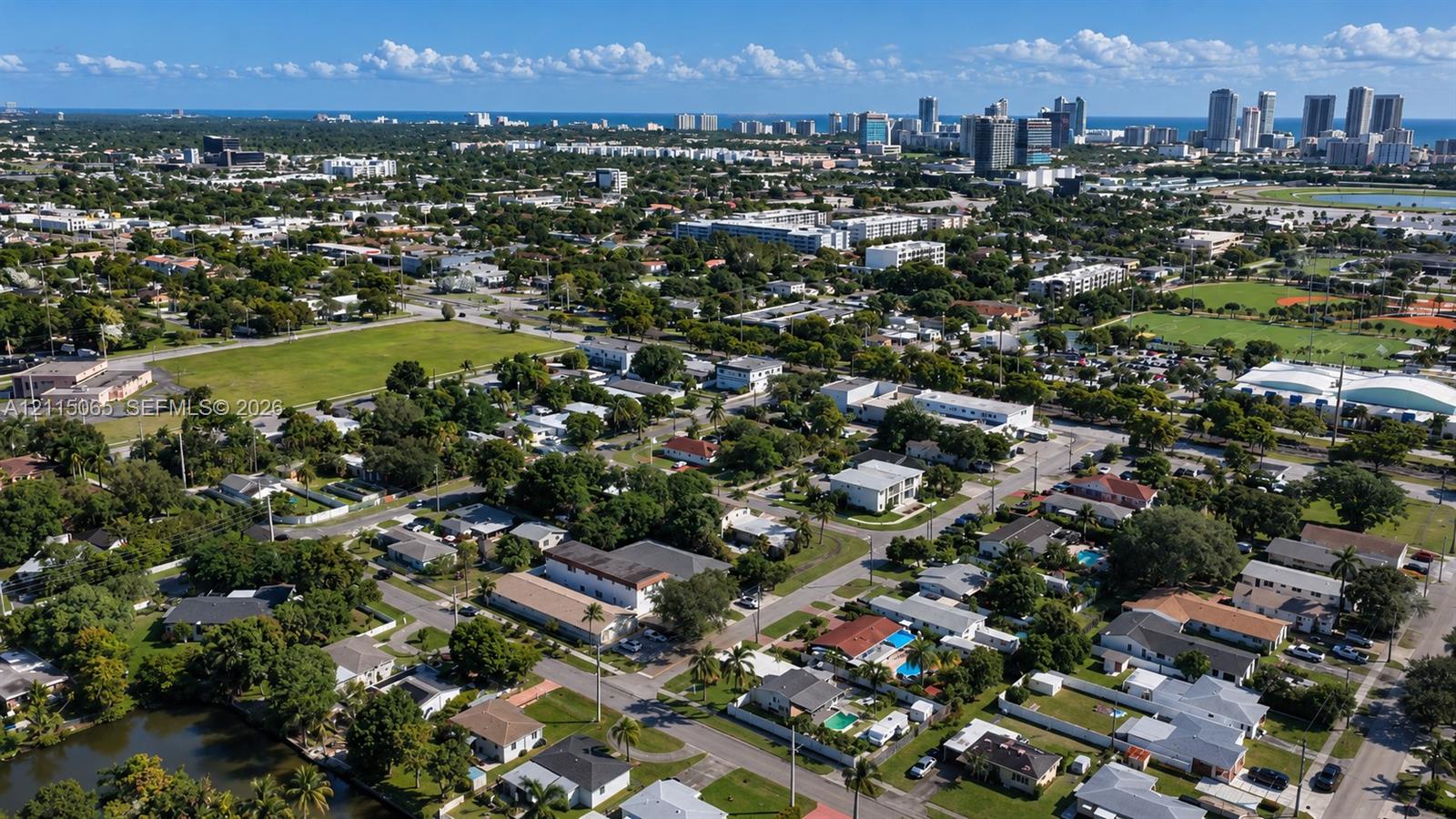Aerial perspective featuring dense mature tree canopy, integrated green spaces, and coastal metropolitan skyline backdrop