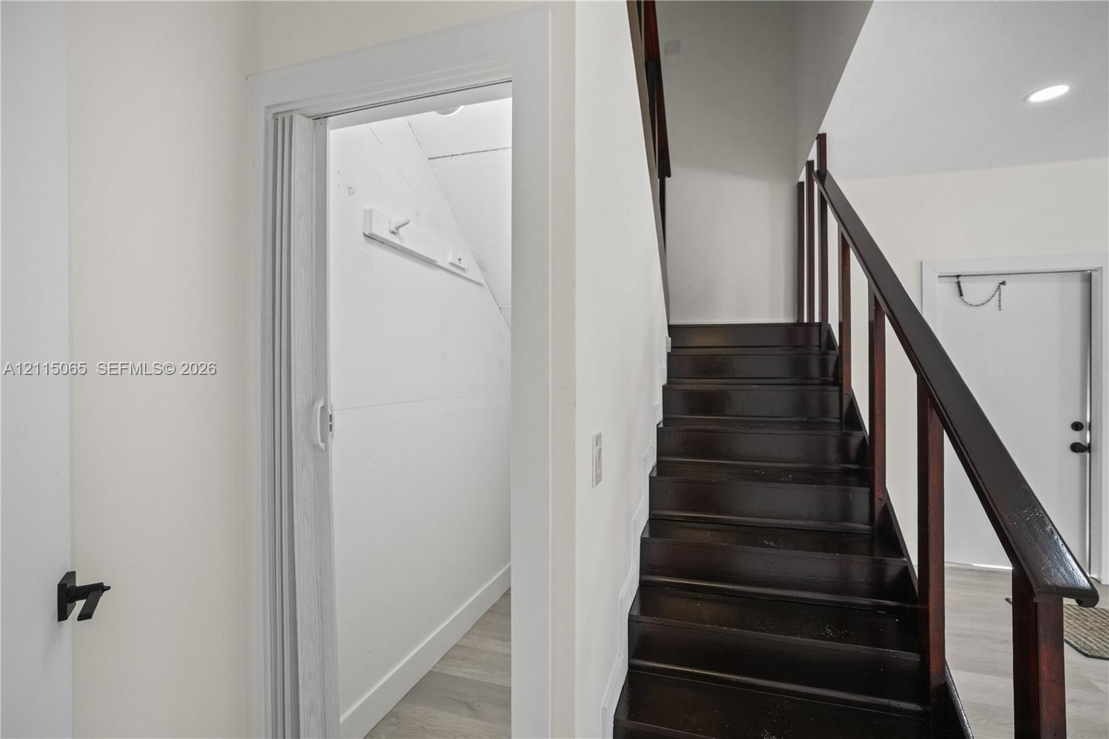 Dark wood staircase with an open-railing banister and neutral-toned wood-finish flooring