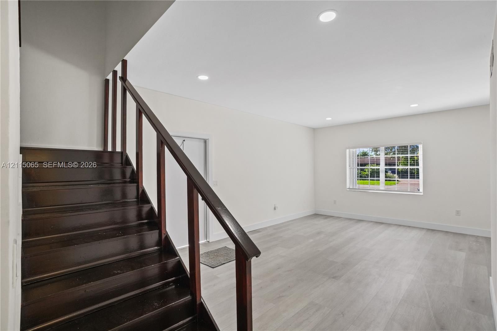Staircase featuring dark wood-finish treads and railings, recessed ceiling lighting, and neutral wood-finish flooring throughout