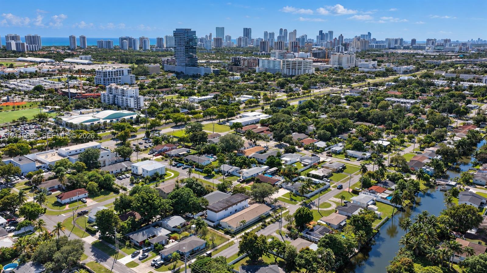 Aerial perspective of residential area featuring a waterway, mature tree canopy, and proximity to the coastal urban skyline